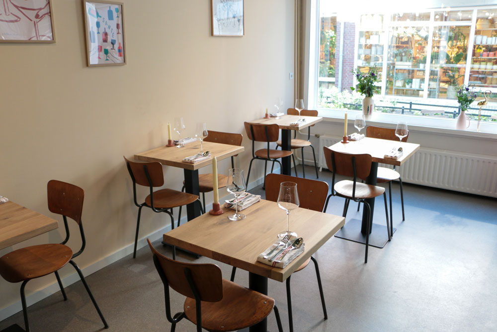 De kleine eetzaal van GIST met houten tafels, kaarsen en daglicht voor de service